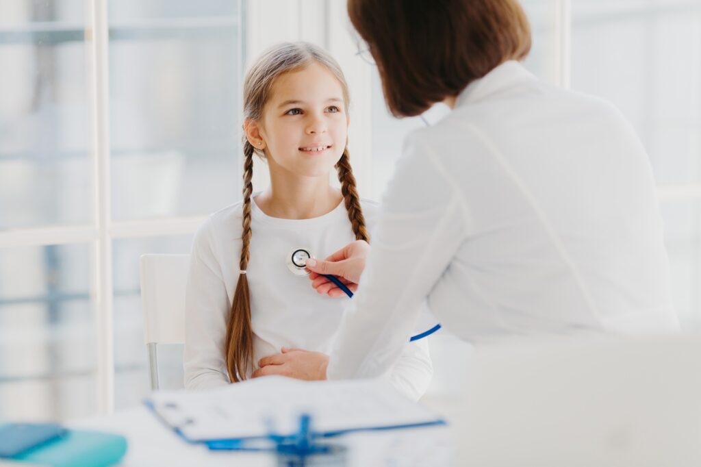 Family general practitioner examines child, listens lungs with stethoscope